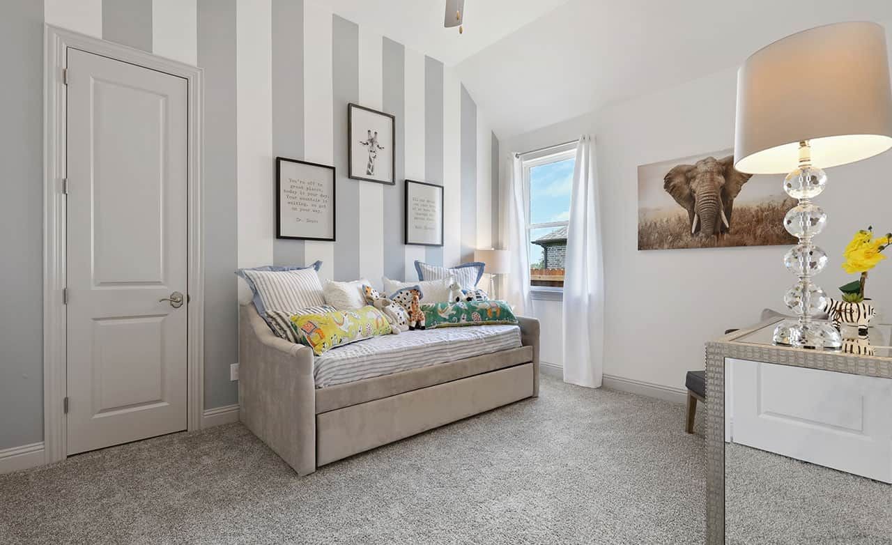 Elegant kids' room in Thompson Farms with gray striped wall, plush daybed, and window.