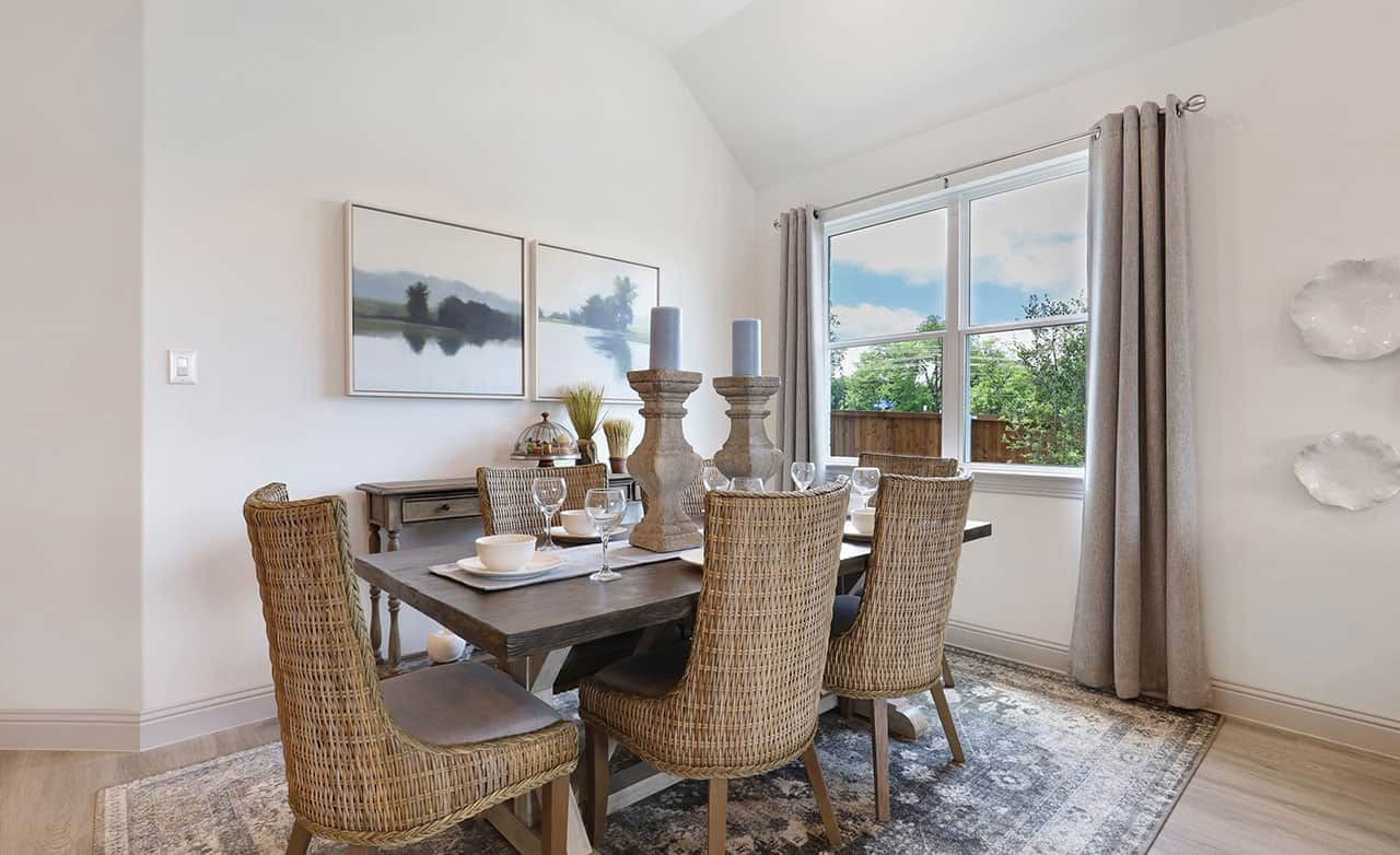 Elegant dining room with woven chairs, rustic table, and large window in Thompson Farms community.