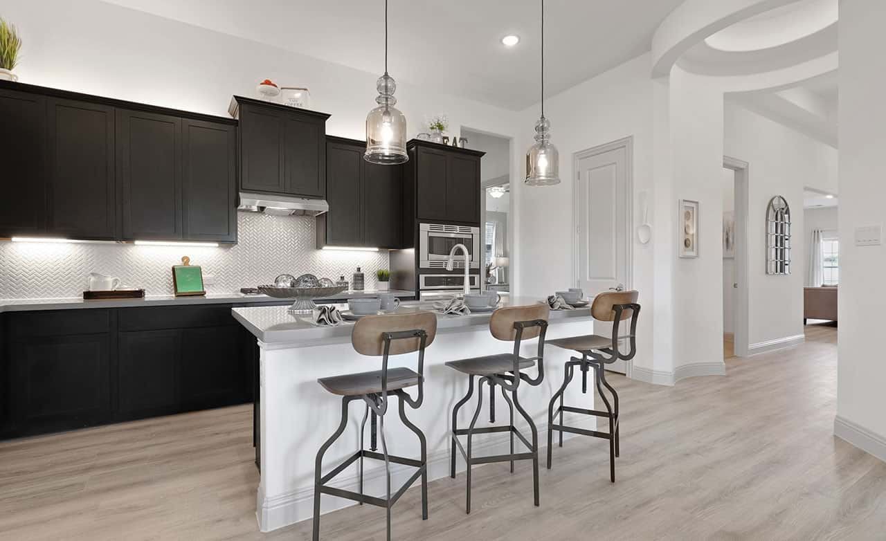 Modern kitchen in Thompson Farms with dark cabinetry, island, pendant lights, herringbone backsplash.
