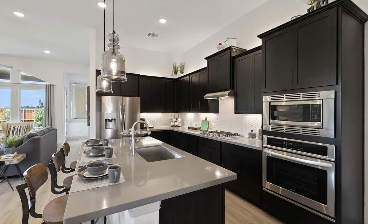 Modern kitchen in Thompson Farms with dark cabinetry, sleek appliances, and pendant lighting.
