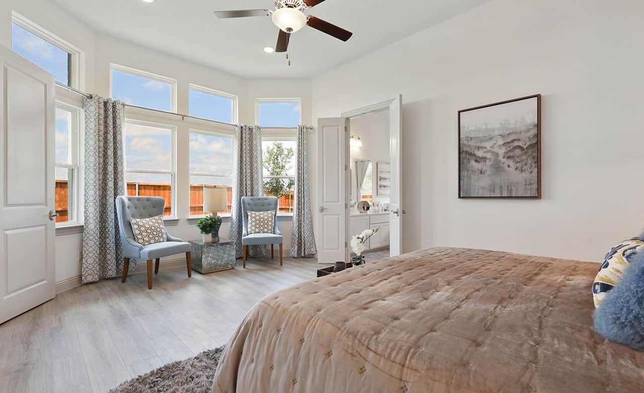 Spacious bedroom with large windows, modern decor, and light wood flooring, located in Thompson Farms community.