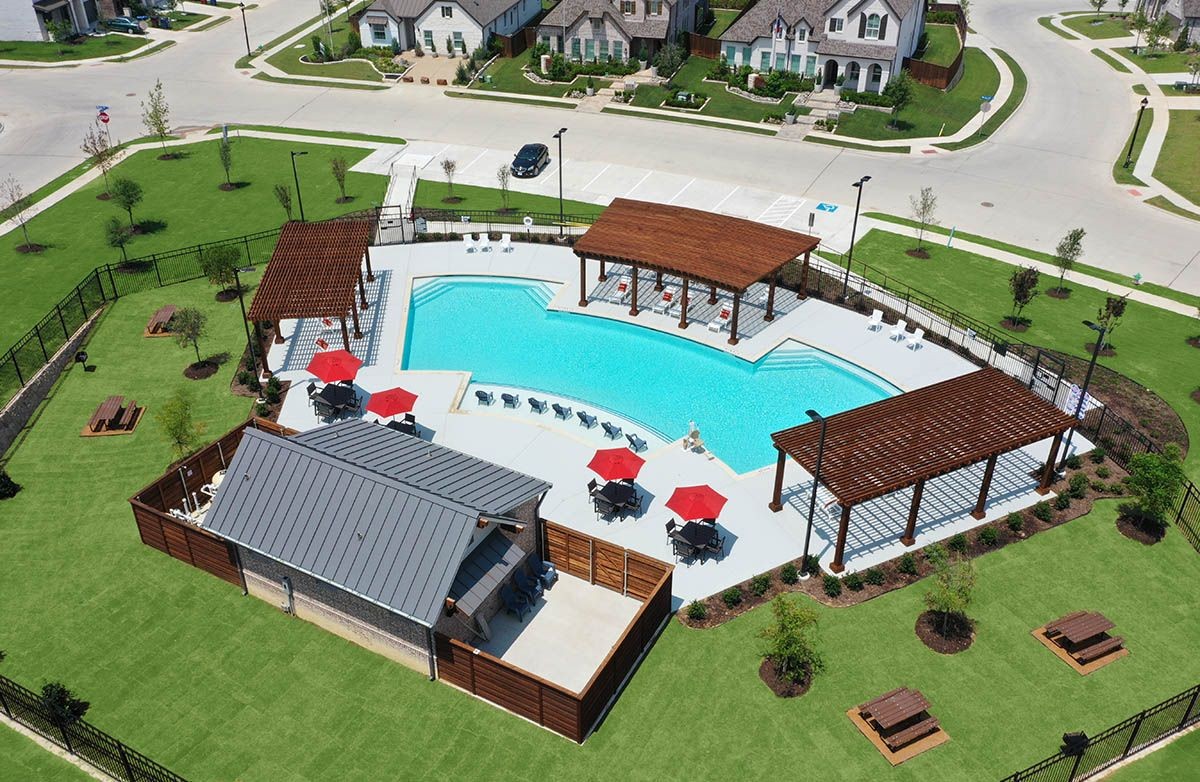 Aerial view of upscale community pool with cabanas, lush lawns, picnic tables, Thompson Farms neighborhood.