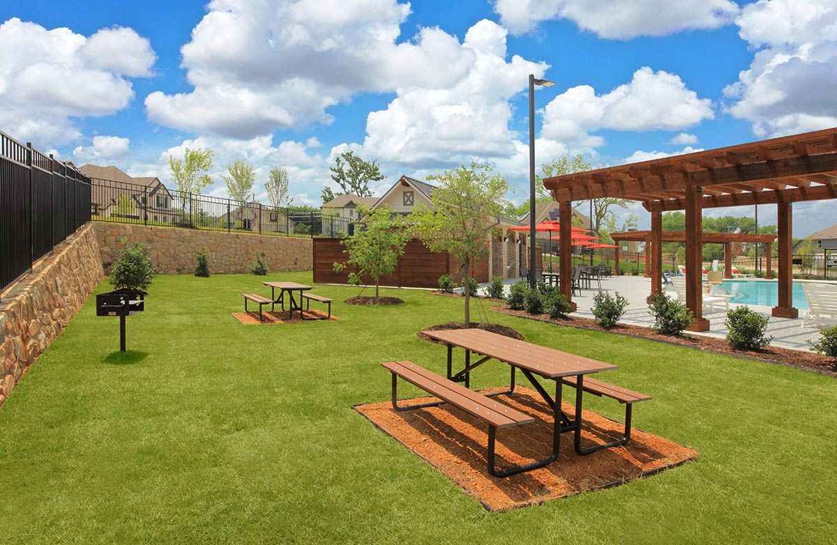 Community park with picnic tables, pergola, pool, and stone wall in Thompson Farms neighborhood.