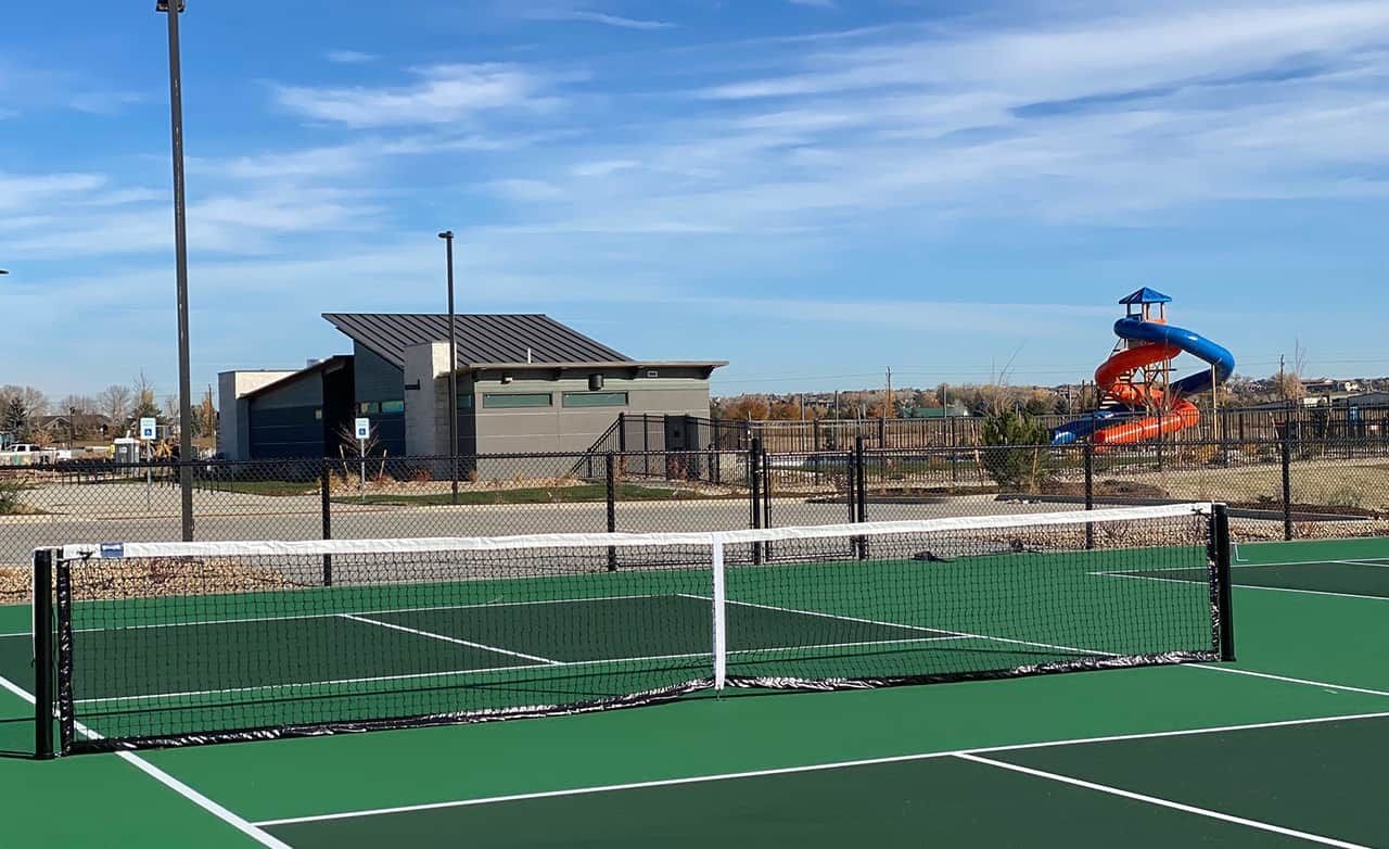 Tennis court with modern clubhouse and colorful slide in Trailside on Harmony, Colorado.