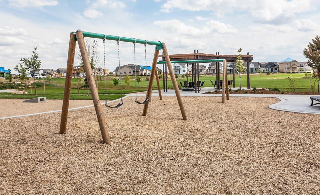 Community park in Trailside on Harmony with swings, pavilion, and houses in the background.