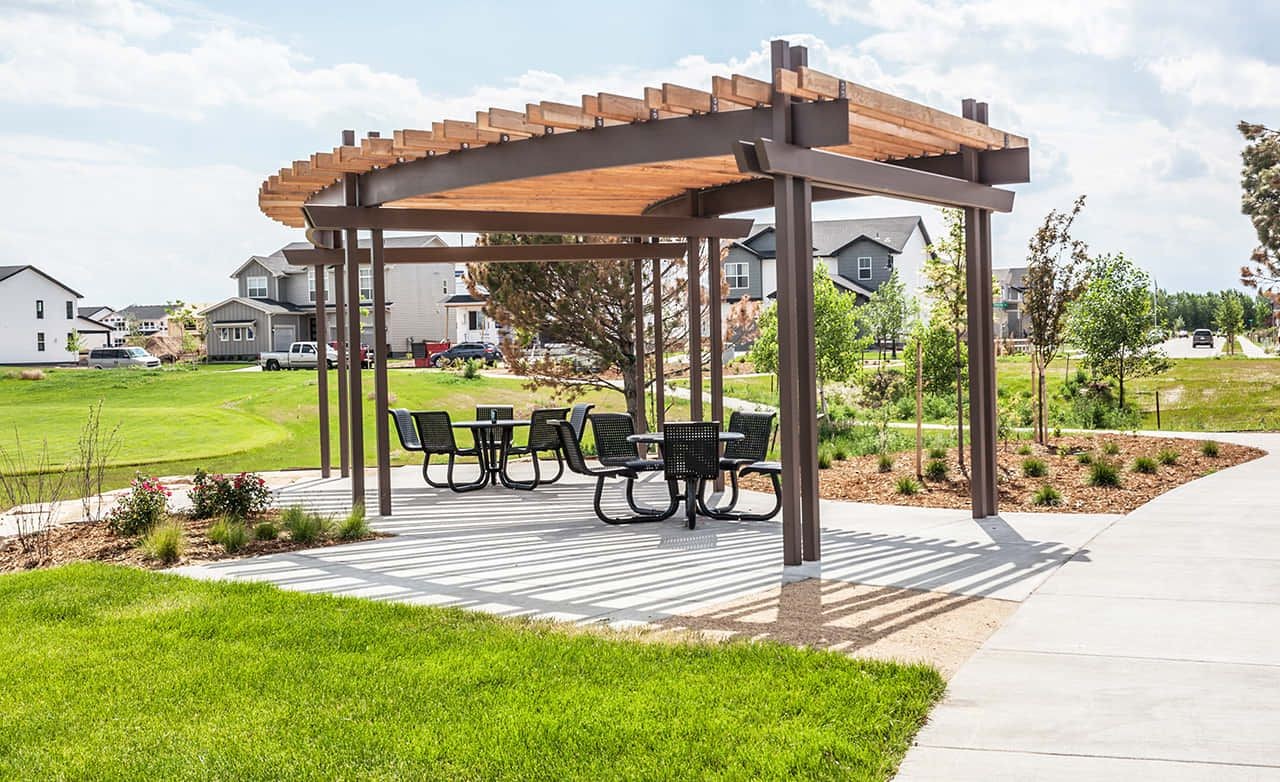 Modern gazebo with wood and metal pergola, seating area, houses in background, Trailside on Harmony community.