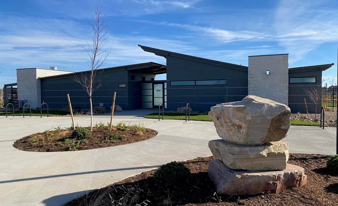 Modern building with large windows, stone accents, and angular roofline in Trailside on Harmony.