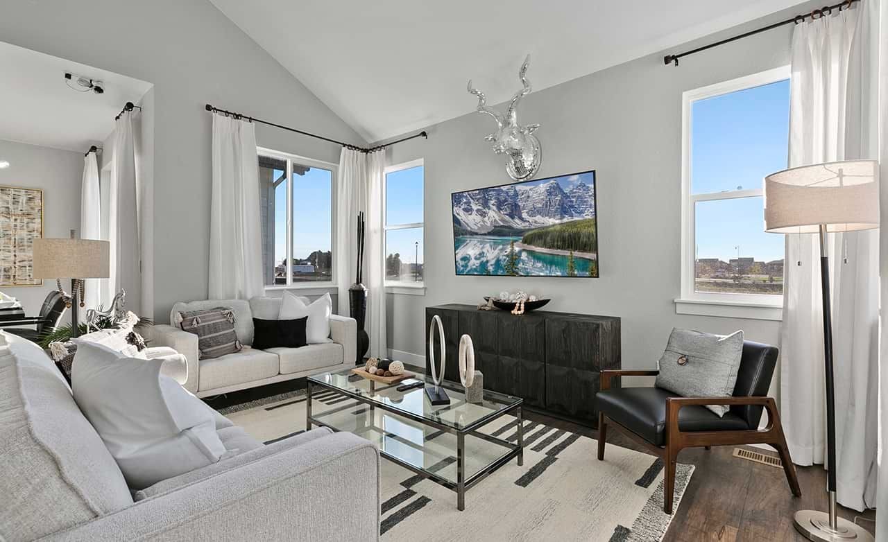 Modern living room with vaulted ceiling, glass coffee table, and scenic artwork in Trailside on Harmony.