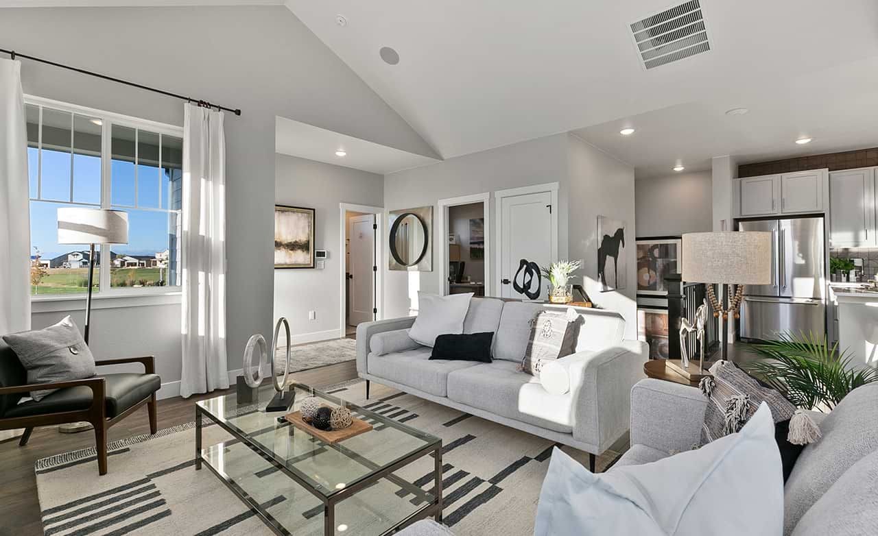 Modern living room with vaulted ceiling, glass coffee table, and large window, Trailside on Harmony, Colorado.