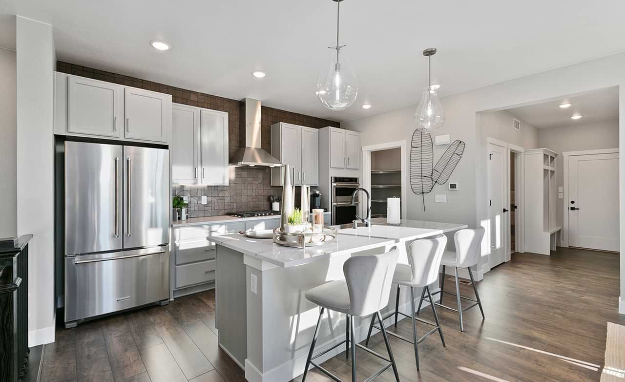 Modern kitchen with island, pendant lights, stainless appliances, and wood flooring. Trailside on Harmony, Colorado.