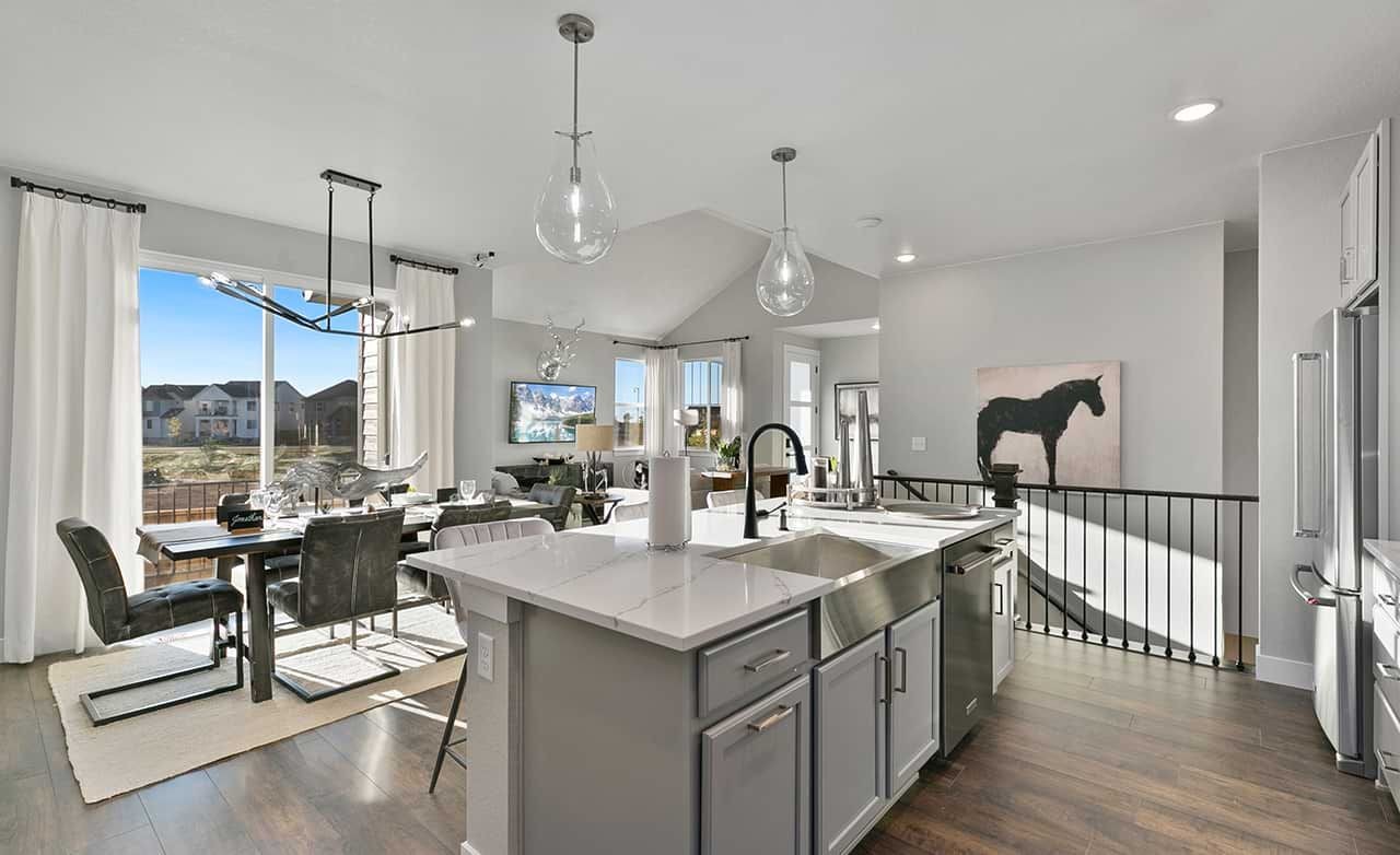 Modern kitchen with marble island, pendant lights, and hardwood floors in Trailside on Harmony, Colorado.