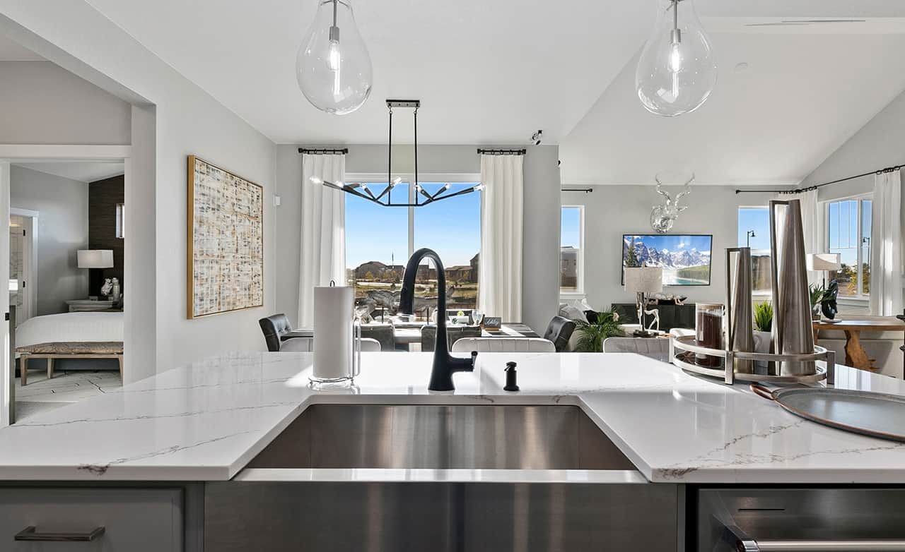 Modern kitchen with marble countertops, sleek black fixtures, and open layout in Trailside on Harmony community.