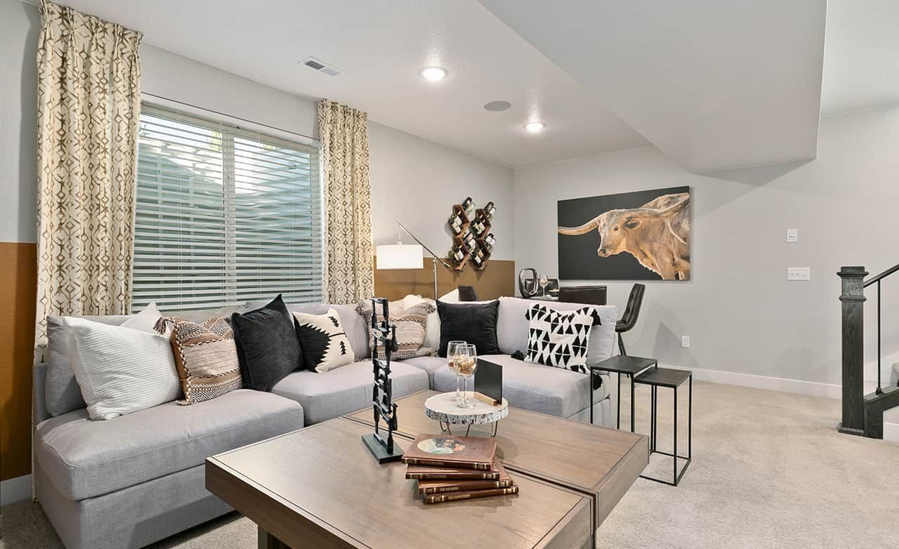 Modern living room with plush sectional, geometric pillows, large window, and bull art. Trailside on Harmony, urban home.