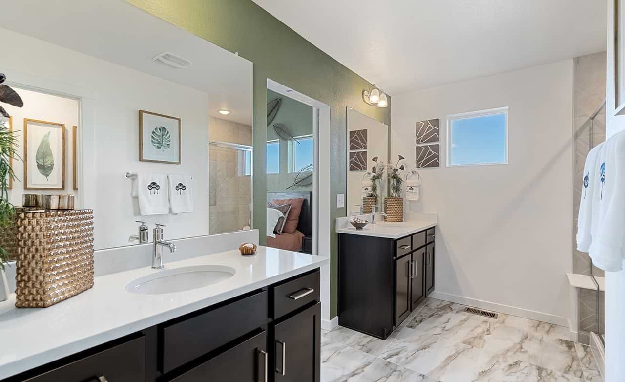 Modern bathroom with double vanity, dark wood cabinets, marble floor in Trailside on Harmony community.