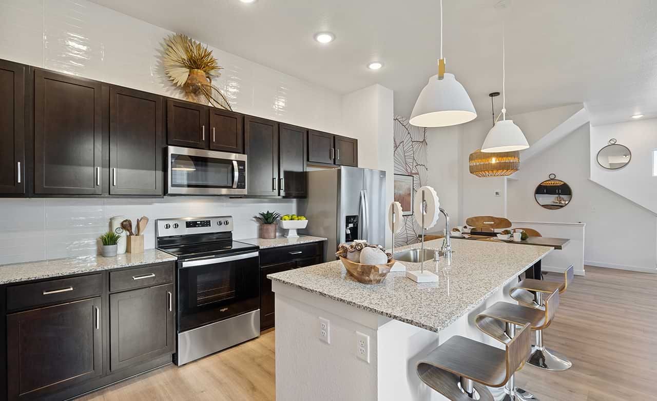 Modern kitchen with dark cabinets, granite countertops, pendant lights. Trailside on Harmony, stylish and elegant design.